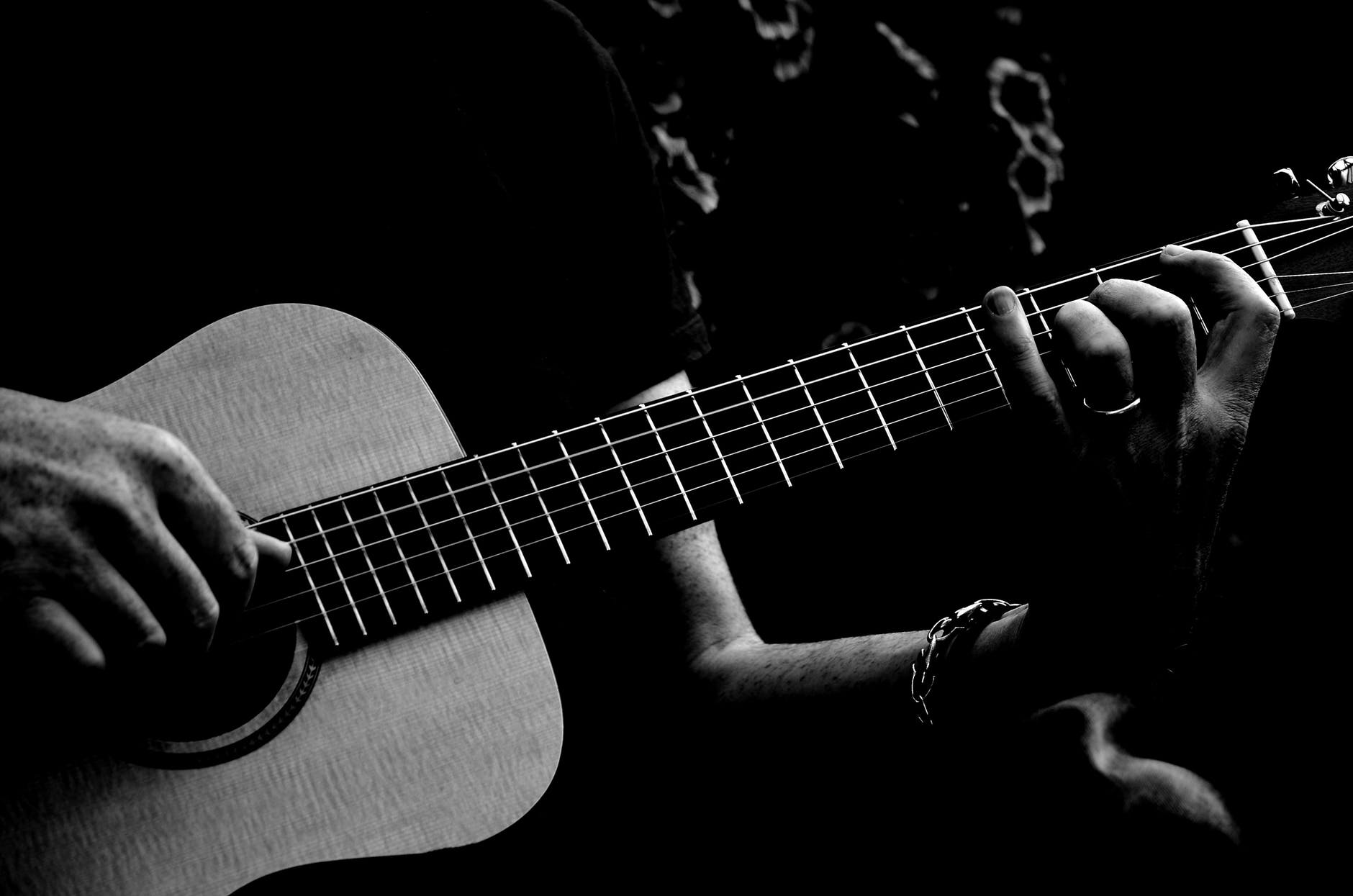 monochrome photo of person playing acoustic guitar