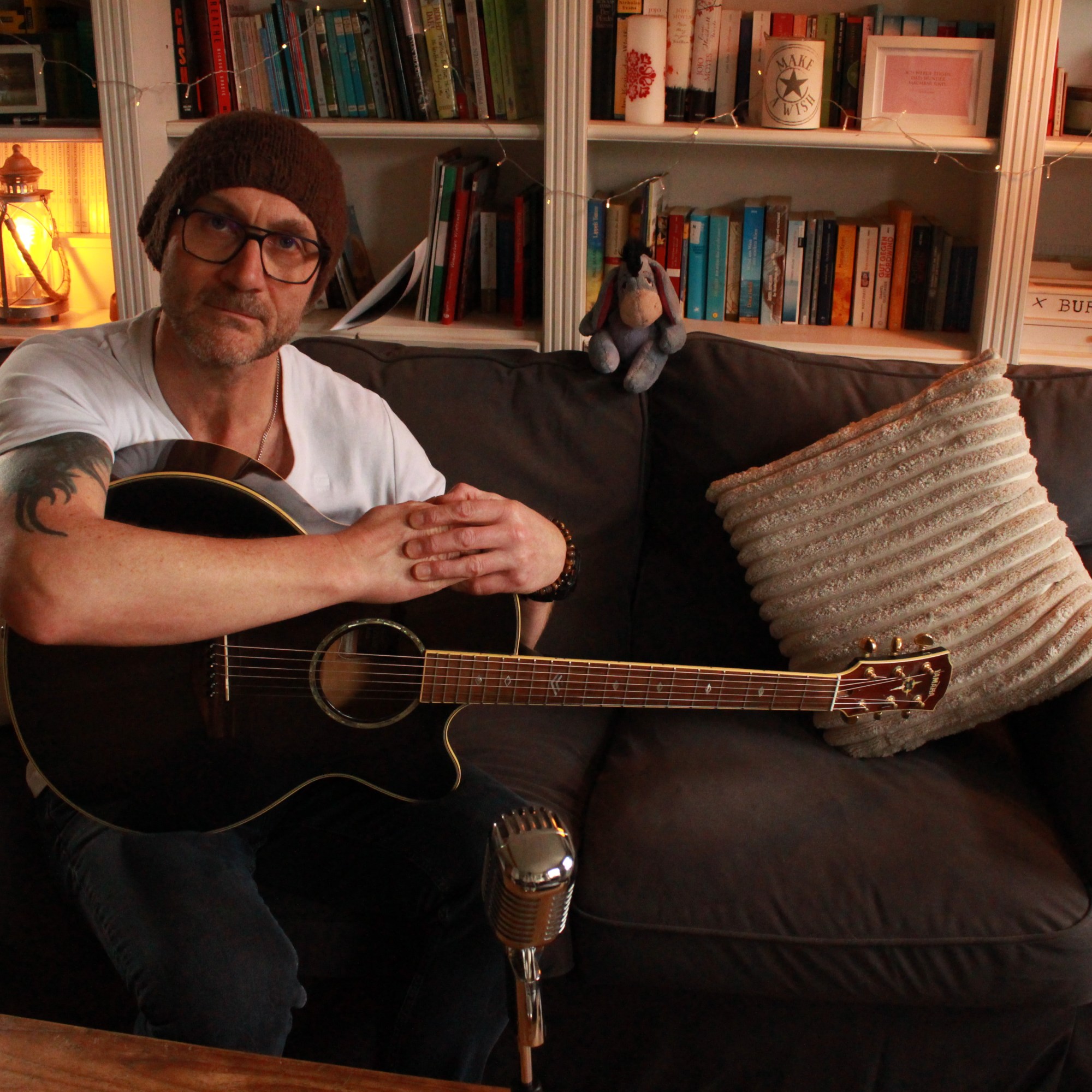Alistair Sings mit Gitarre auf dem Sofa